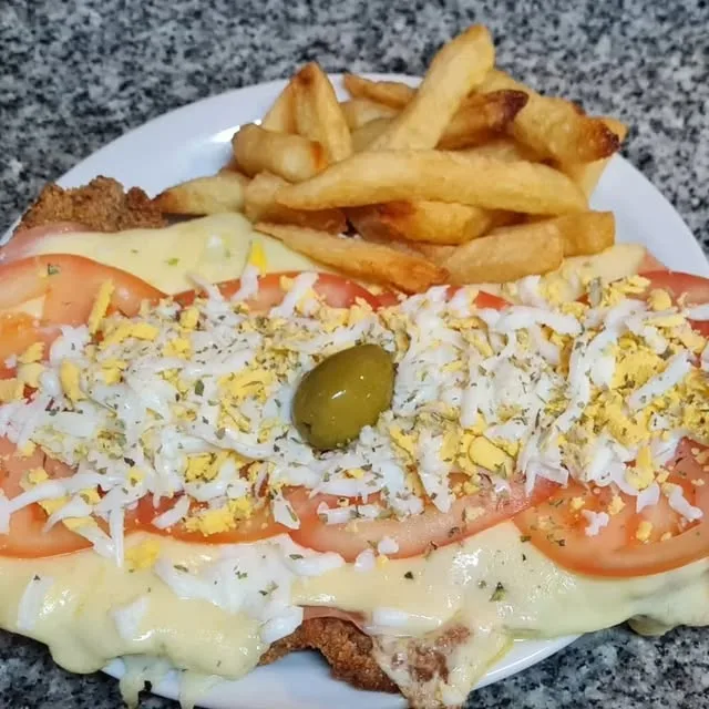 Milanesa con jamón, queso, tomate y huevo, acompañada de papas fritas