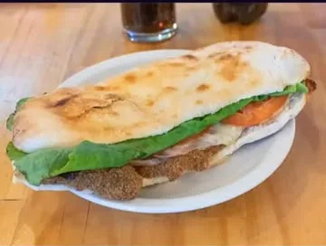 Sándwich de milanesa con lechuga, tomate y jamón